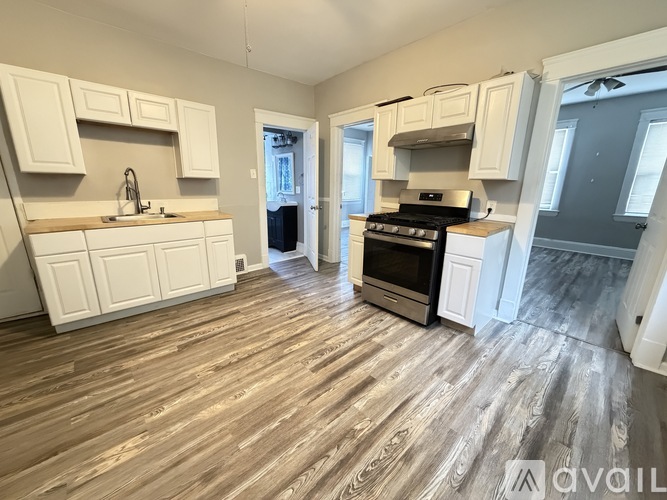 A kitchen with white cabinets and a wooden floor.