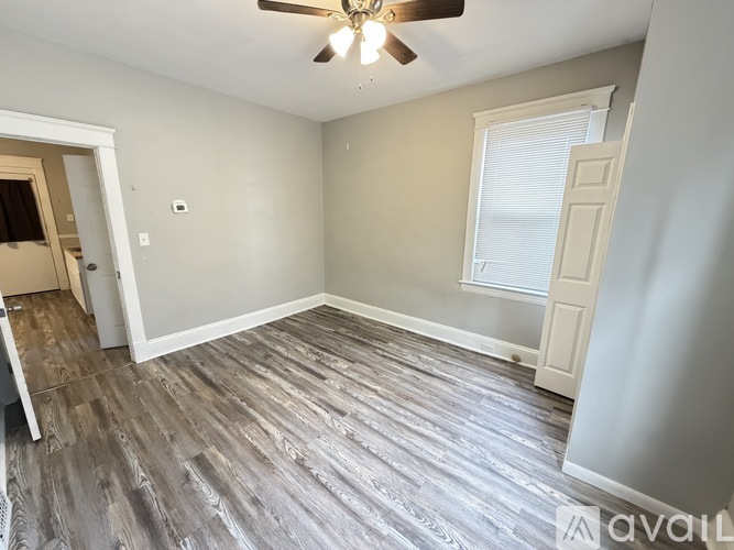 A room with a ceiling fan and a window with blinds.