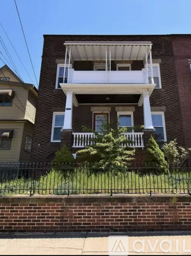 A brick building with a balcony and a black fence.