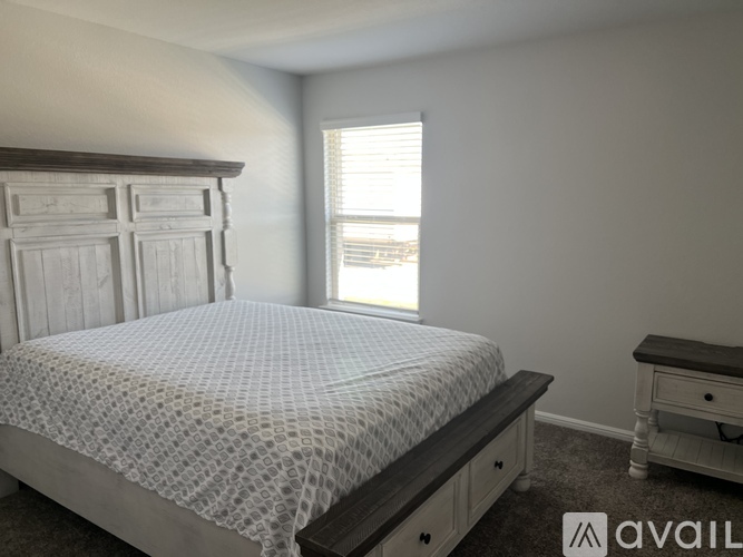 A bedroom with a bed, nightstand, and window.