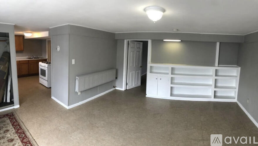 A spacious room with a kitchen area to the left and a pantry to the right.
