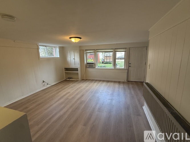A room with wooden flooring and white walls is available for rent.