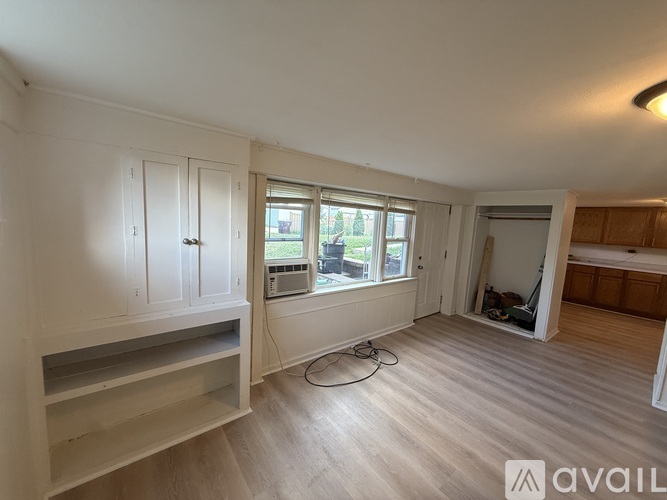 A room with a window, a shelf, and a doorway leading to another room.