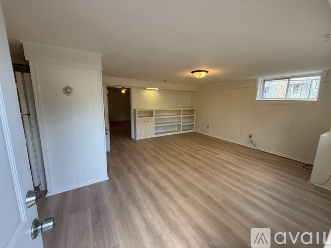 A room with wooden flooring and a window with blinds.