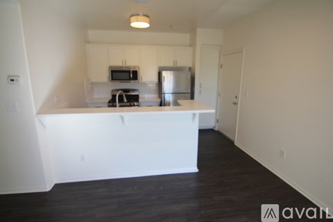 A kitchen with white cabinets and appliances in a room with hardwood floors.