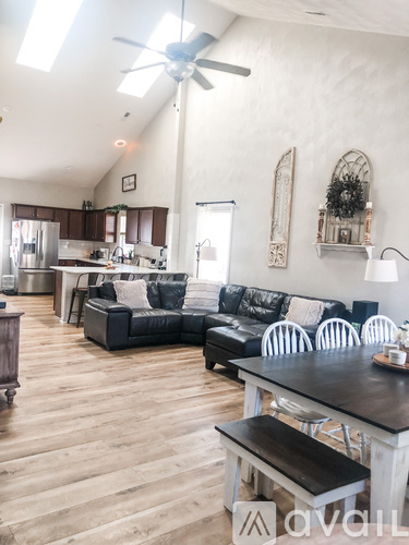 A living room with a black couch and a wooden floor.