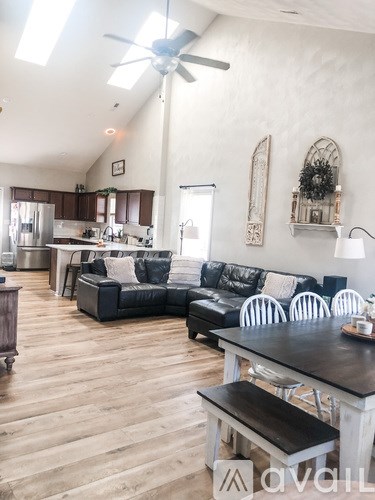 A living room with a black couch and a wooden floor.