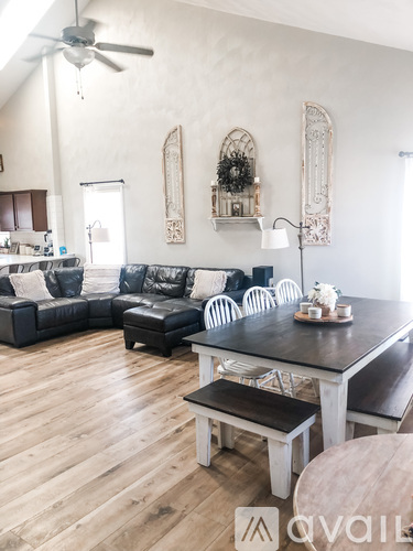 A living room with a black couch and a wooden dining table.