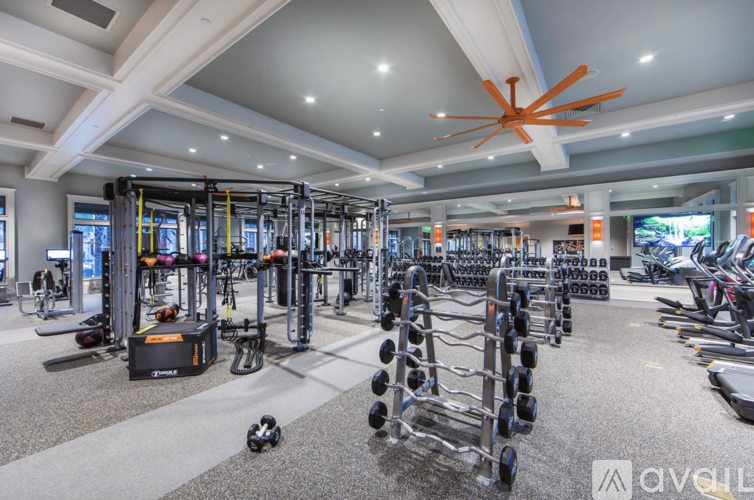 A gym with a variety of equipment including dumbbells, weight machines, and a television.