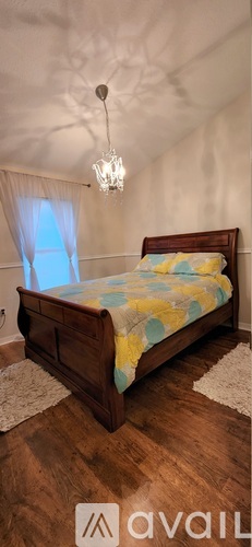 A bedroom with a bed and a chandelier.