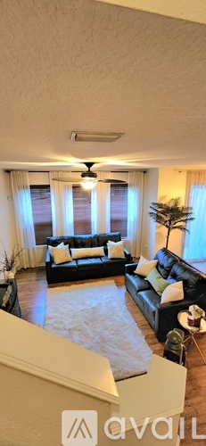 A living room with a black couch and a ceiling fan.