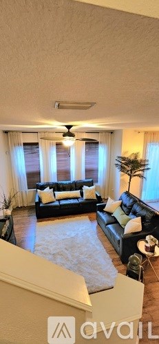A living room with a black couch and a ceiling fan.