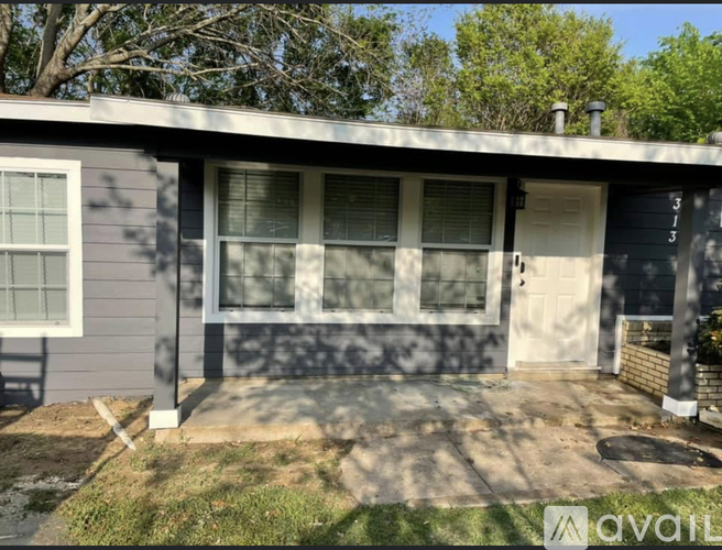 A house with a grey front and a white door is for sale.