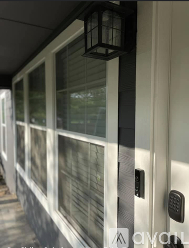 A white door with a black handle and a black lantern hanging above it.