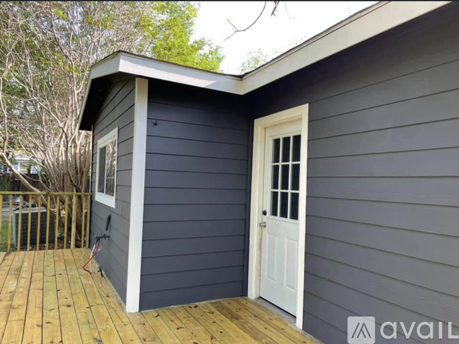 A small house with a white door and a wooden deck.