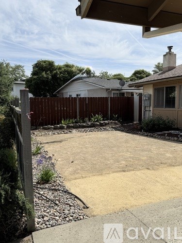 A backyard with a fence and a house in the background.