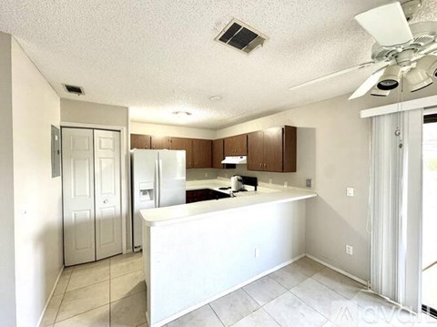 A kitchen with white appliances and a white ceiling fan.