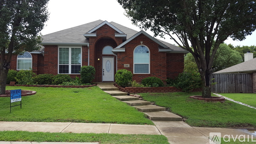 A brick house with a white door and a sign in front.