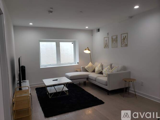 A living room with a white couch, a black rug, and a wooden chair.