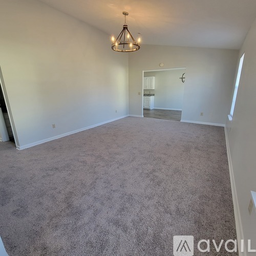 A spacious room with a carpeted floor and a chandelier hanging from the ceiling.