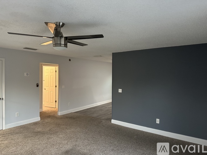 A room with a ceiling fan and a door leading to another room.