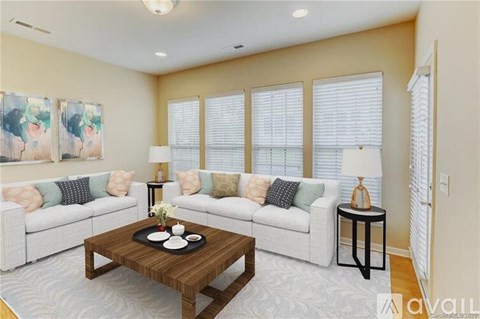 A living room with a white couch, a wooden coffee table, and a painting on the wall.