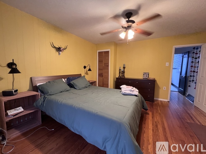 A bedroom with a bed, nightstand, and a deer head on the wall.
