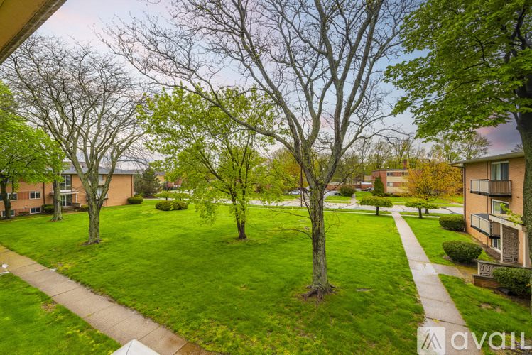 A grassy area with trees and apartment buildings in the background.