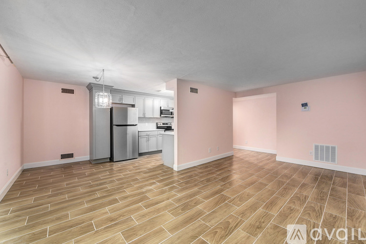 A spacious room with pink walls and a wooden floor.