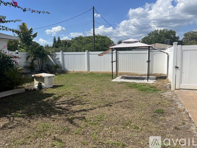 A backyard with a white fence and a white gazebo.