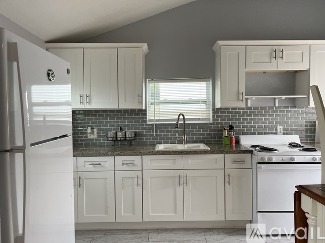 A kitchen with white cabinets and a white refrigerator.