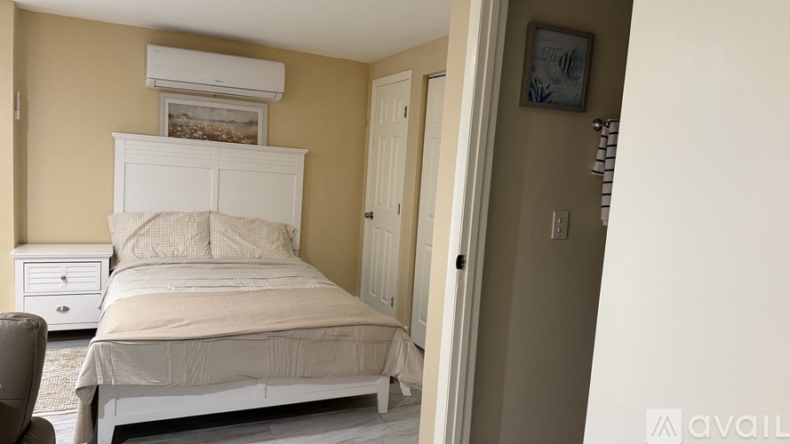 A bedroom with a white bed and a white nightstand.