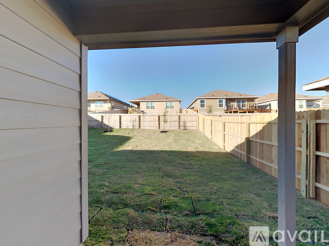 A view from a covered patio looking out to a grassy yard and houses.