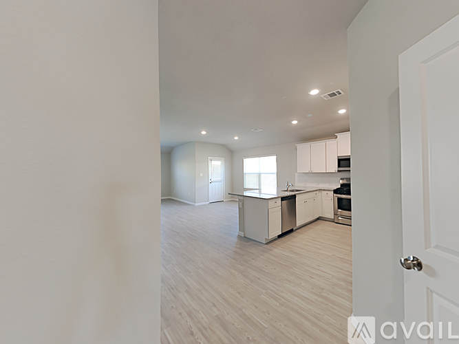 A spacious kitchen and living room with white cabinets and a hardwood floor.