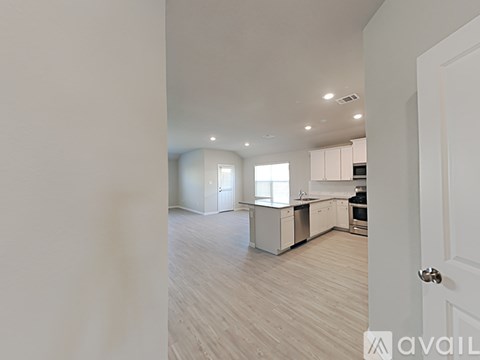 A spacious kitchen and living room with white cabinets and a hardwood floor.