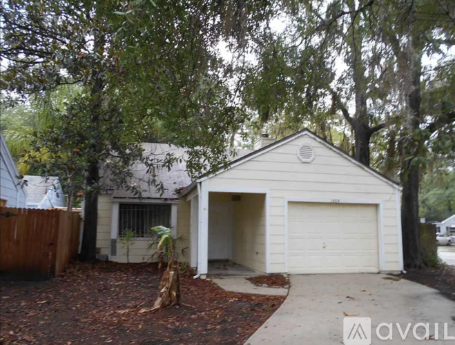 A house with a white garage door is surrounded by trees.