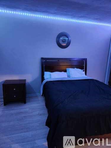 A bedroom with a bed, nightstand, and a round mirror on the wall.