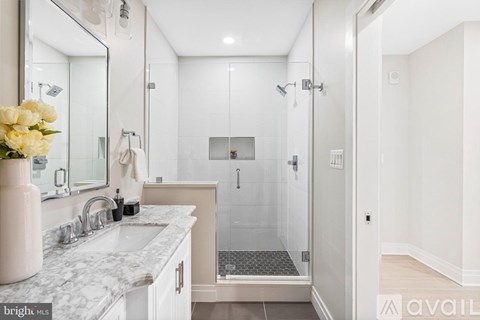 A bathroom with a marble countertop and a walk-in shower.