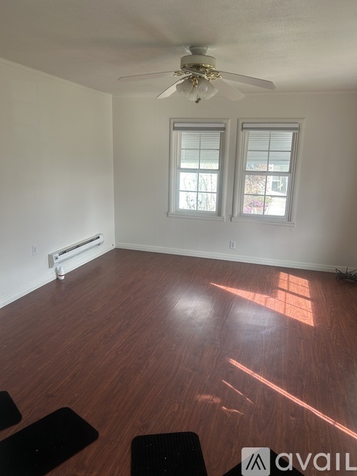 A room with a ceiling fan and two windows.