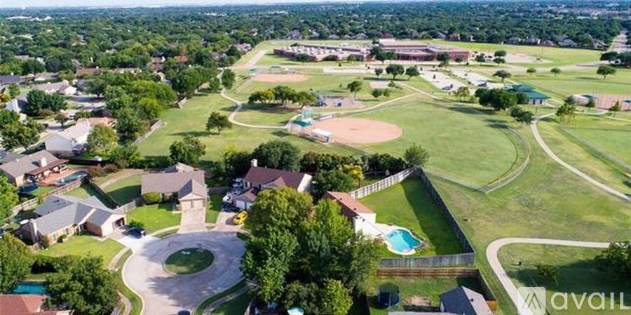 A bird's eye view of a residential area with a swimming pool and a football field.