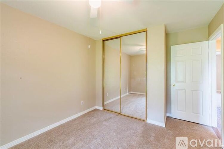A bedroom with a carpeted floor and a large mirror on the wall.