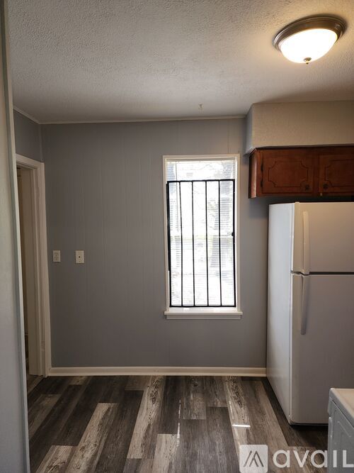 A kitchen with a refrigerator and a window with bars.
