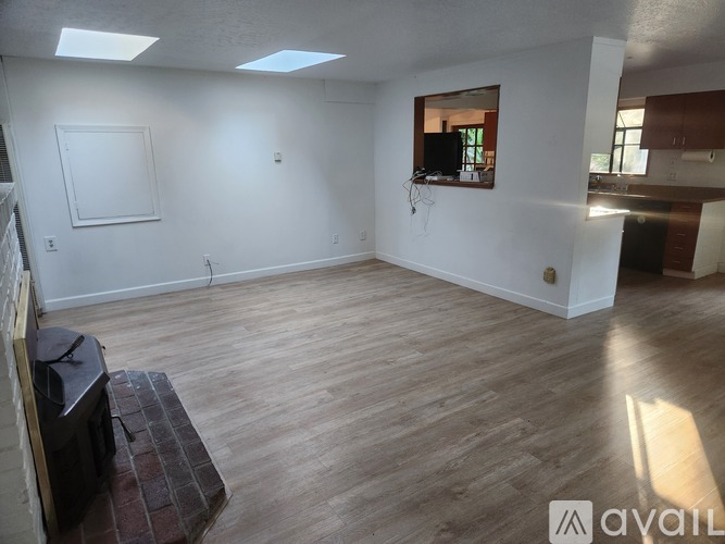 A spacious room with wooden flooring and a brick fireplace.