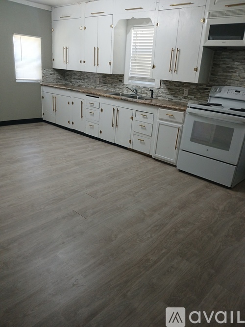 A kitchen with white cabinets and a wooden floor.