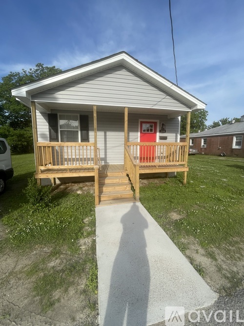A small house with a red door and a porch.