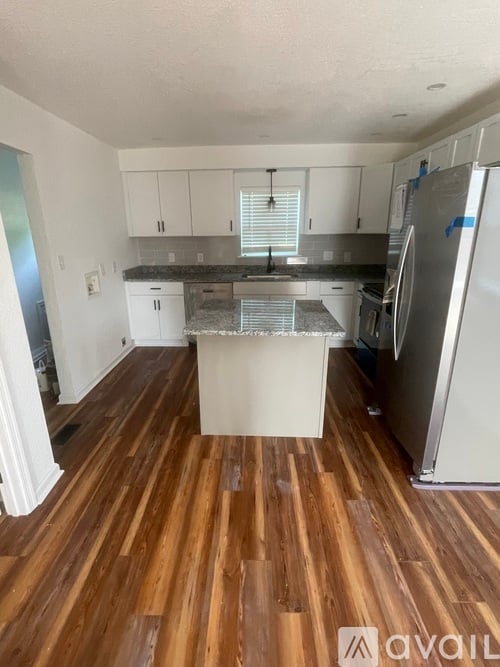 A kitchen with wooden floors and white cabinets.