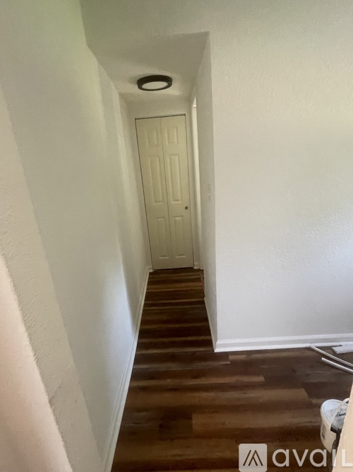 A hallway with a white door and wooden floors.