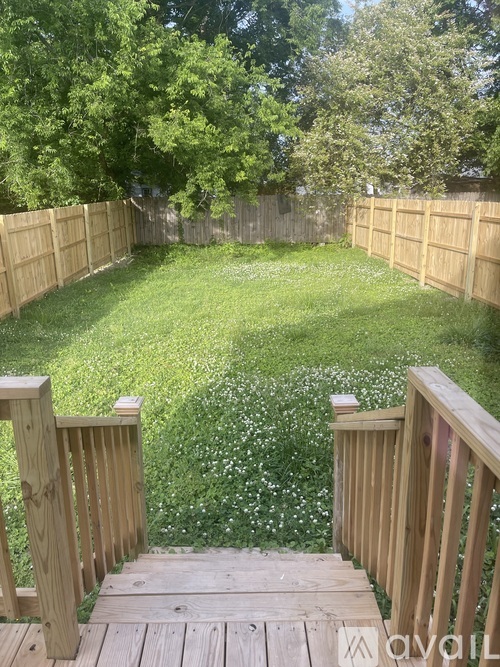 A backyard with a wooden deck and a grassy area.