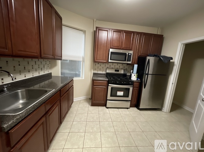 A kitchen with brown cabinets and a stainless steel refrigerator.