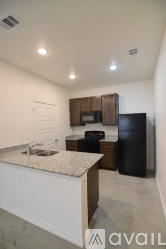 A kitchen with a granite countertop and a black refrigerator.